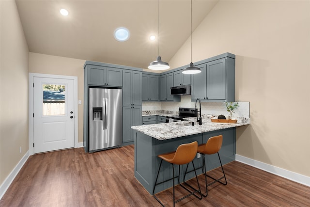 kitchen featuring a kitchen breakfast bar, decorative light fixtures, appliances with stainless steel finishes, kitchen peninsula, and sink