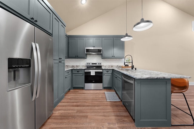 kitchen with pendant lighting, appliances with stainless steel finishes, a kitchen bar, kitchen peninsula, and sink