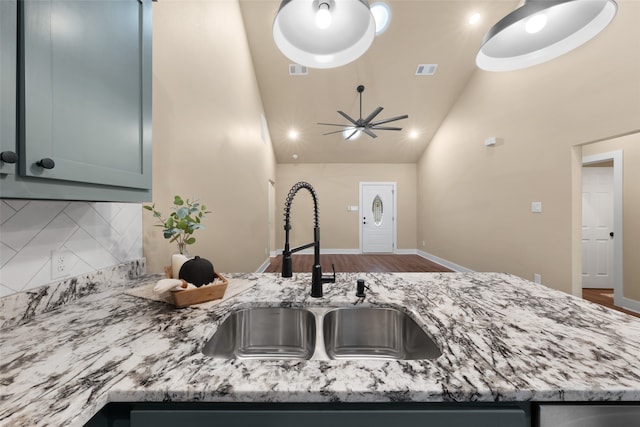 kitchen featuring light stone counters, ceiling fan, sink, high vaulted ceiling, and tasteful backsplash