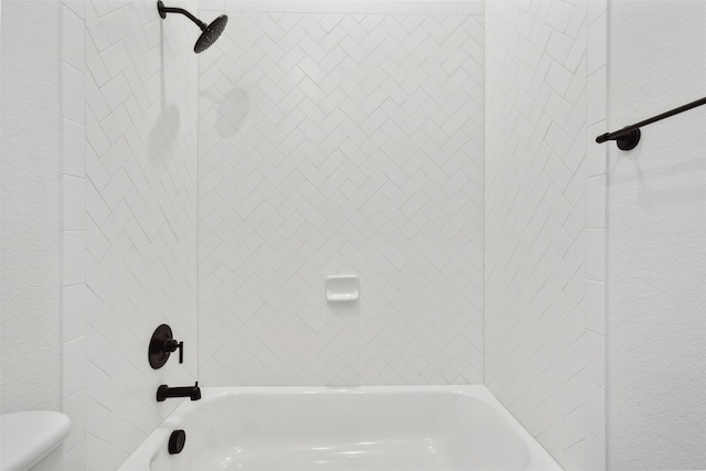 bathroom with toilet and tiled shower / bath