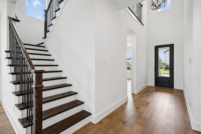 entrance foyer with hardwood / wood-style floors, a high ceiling, and an inviting chandelier