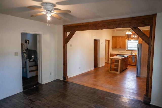 unfurnished living room with ceiling fan, sink, and dark hardwood / wood-style flooring