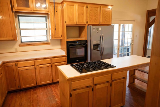 kitchen with a center island, black appliances, light countertops, and dark wood-style flooring