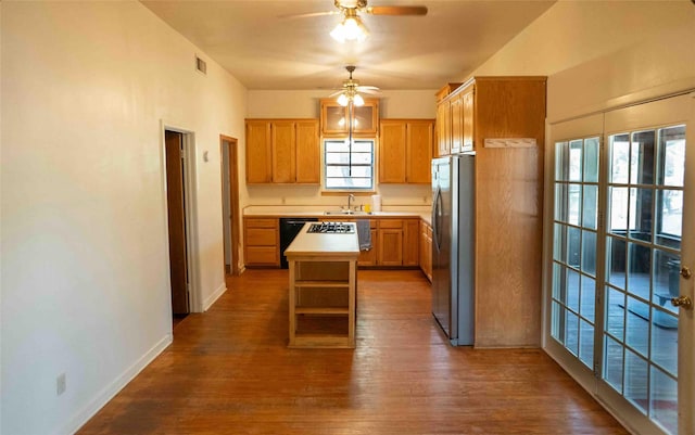 kitchen with dark wood-style floors, a center island, freestanding refrigerator, light countertops, and ceiling fan