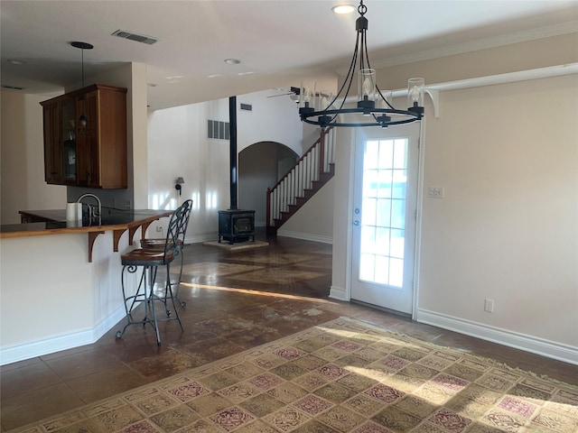 kitchen with a kitchen bar, kitchen peninsula, a wood stove, and a notable chandelier