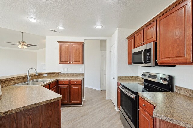 kitchen featuring light wood-type flooring, a textured ceiling, stainless steel appliances, sink, and ceiling fan