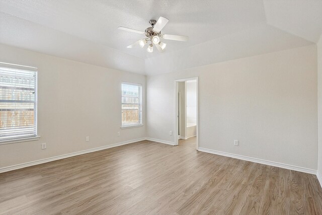 empty room featuring vaulted ceiling, a textured ceiling, light hardwood / wood-style flooring, and ceiling fan