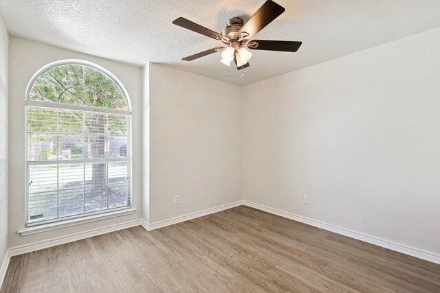 spare room with a textured ceiling, ceiling fan, and light wood-type flooring