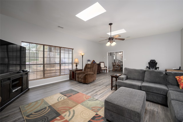 living room with hardwood / wood-style floors, a skylight, and ceiling fan