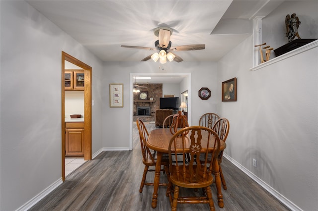 dining room with ceiling fan, wood-type flooring, and a fireplace