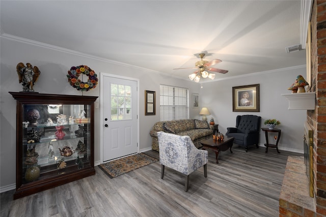 living room with hardwood / wood-style floors, a brick fireplace, ceiling fan, and crown molding