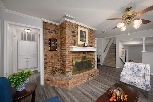 living room featuring ceiling fan, a brick fireplace, dark hardwood / wood-style floors, a textured ceiling, and ornamental molding