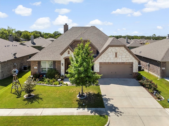 view of front of house with a front lawn, a garage, and central AC unit