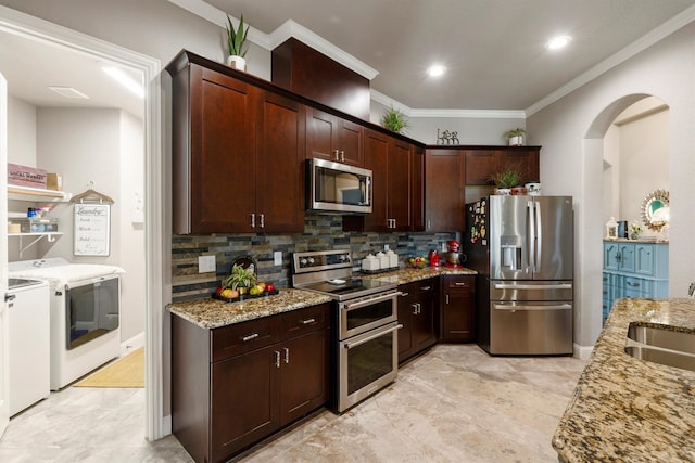 kitchen with washing machine and clothes dryer, stainless steel appliances, light stone countertops, and decorative backsplash