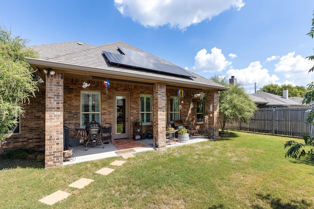 rear view of property with a yard, solar panels, and a patio area