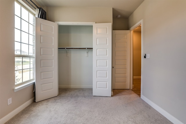 unfurnished bedroom featuring a closet and light carpet