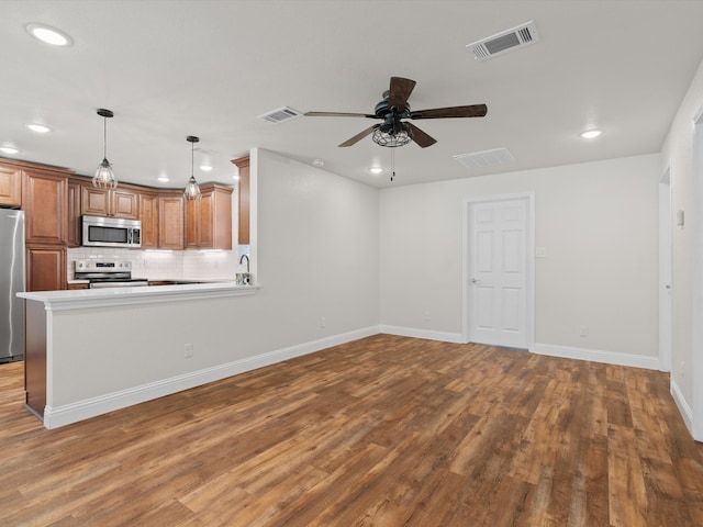 interior space featuring backsplash, stainless steel appliances, wood-type flooring, ceiling fan, and pendant lighting