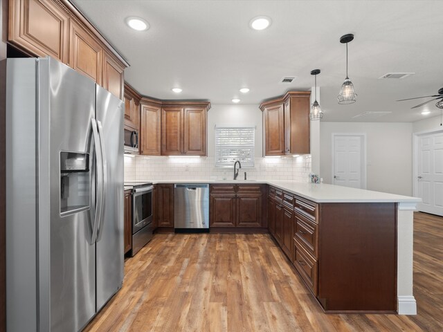 kitchen with wood-type flooring, kitchen peninsula, stainless steel appliances, and ceiling fan