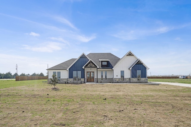 modern farmhouse with roof with shingles, a front yard, board and batten siding, and french doors