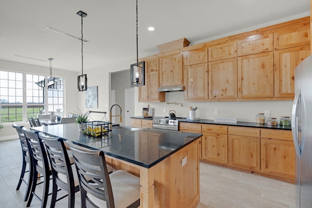 kitchen featuring an inviting chandelier, appliances with stainless steel finishes, a kitchen island with sink, sink, and light brown cabinets