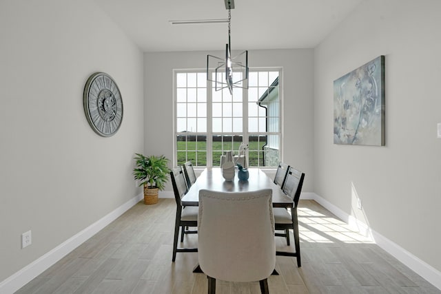 dining area with light wood-type flooring and a chandelier