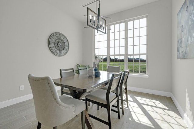 dining room with a notable chandelier, light wood-style flooring, and baseboards