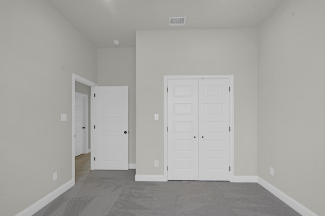 unfurnished bedroom with light colored carpet and a closet