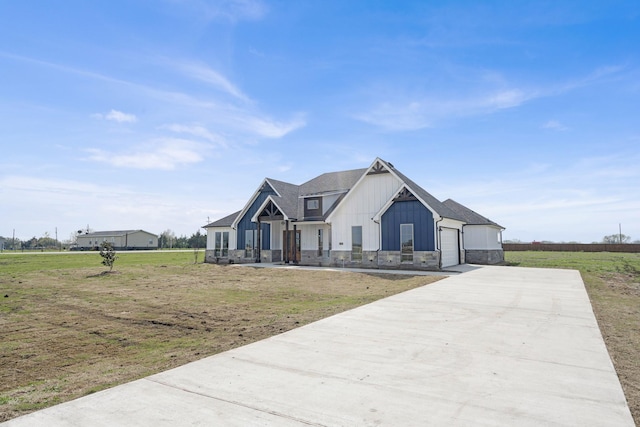 modern farmhouse featuring a garage, driveway, roof with shingles, a front lawn, and board and batten siding