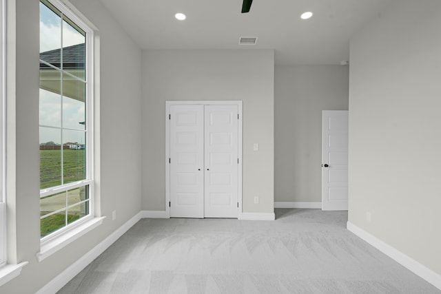 unfurnished bedroom featuring light carpet, ceiling fan, and a closet