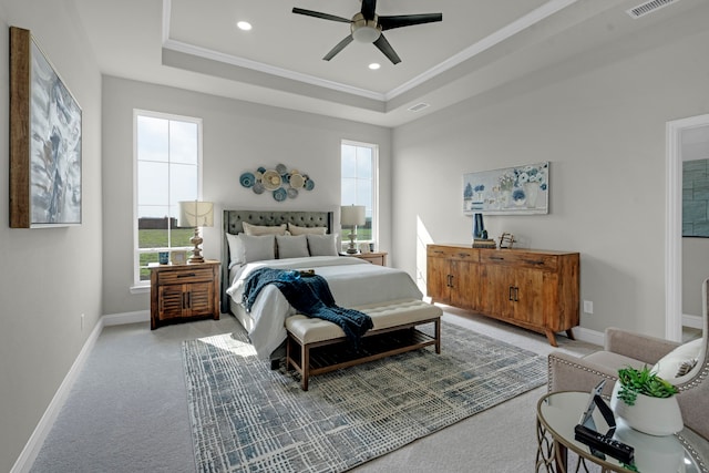 carpeted bedroom with a tray ceiling, ornamental molding, and ceiling fan