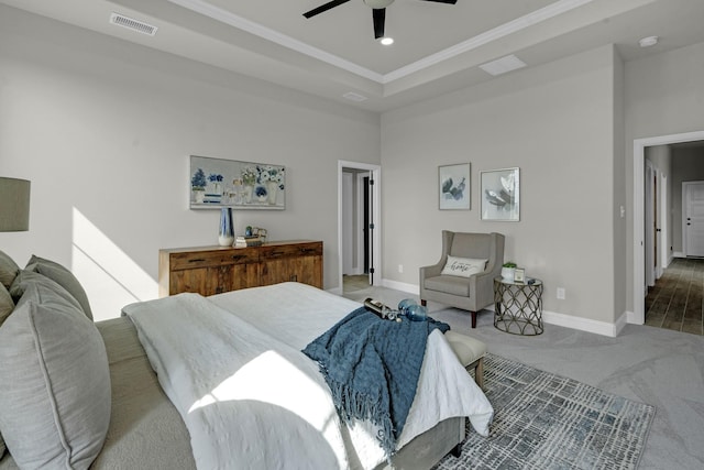 carpeted bedroom featuring a tray ceiling, visible vents, baseboards, and crown molding