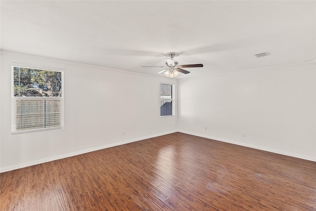 spare room with dark wood-type flooring, visible vents, plenty of natural light, and baseboards