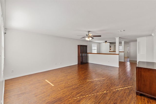 unfurnished living room with baseboards, visible vents, wood finished floors, and ornamental molding