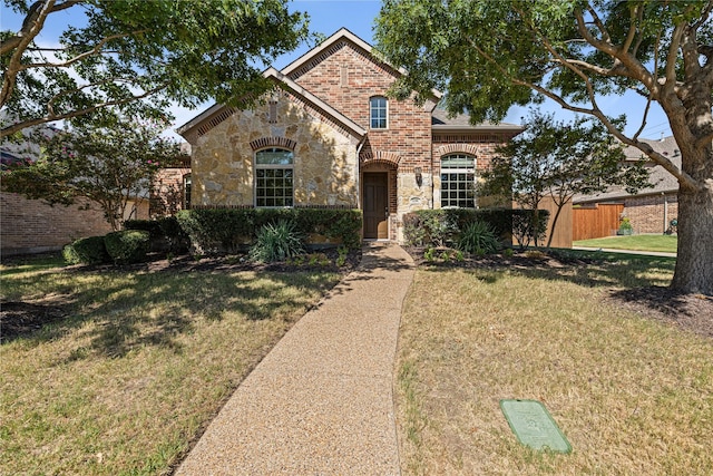 view of front of property featuring stone siding, a front yard, fence, and brick siding