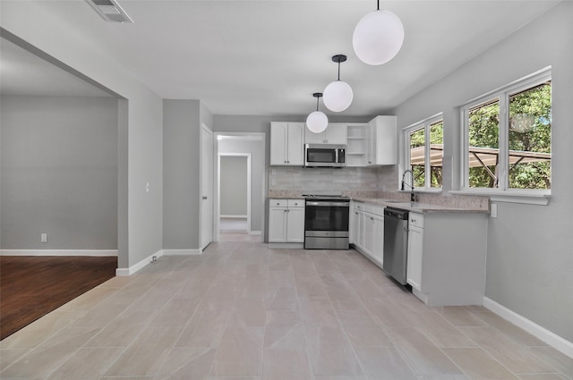 kitchen featuring light wood-type flooring, tasteful backsplash, white cabinets, hanging light fixtures, and appliances with stainless steel finishes