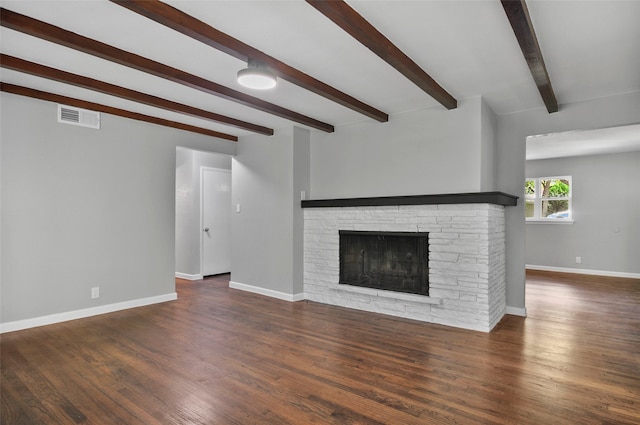 unfurnished living room with a stone fireplace, beam ceiling, and dark hardwood / wood-style floors