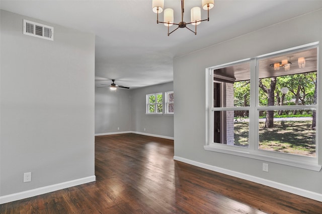 empty room featuring ceiling fan with notable chandelier and dark wood-type flooring