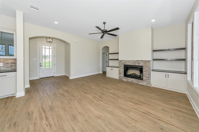 unfurnished living room featuring a fireplace, light hardwood / wood-style flooring, and ceiling fan