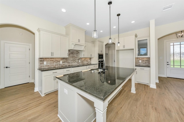 3043 Sunrise Trl, Weatherford, TX 76088 - kitchen with visible vents, light wood-style floors, arched walkways, white cabinets, and a sink
