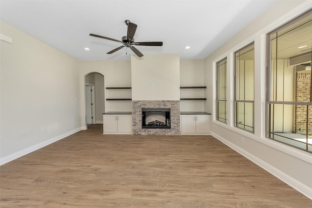 3043 Sunrise Trl, Weatherford, TX 76088 - unfurnished living room featuring light wood-type flooring, arched walkways, baseboards, a brick fireplace, and ceiling fan