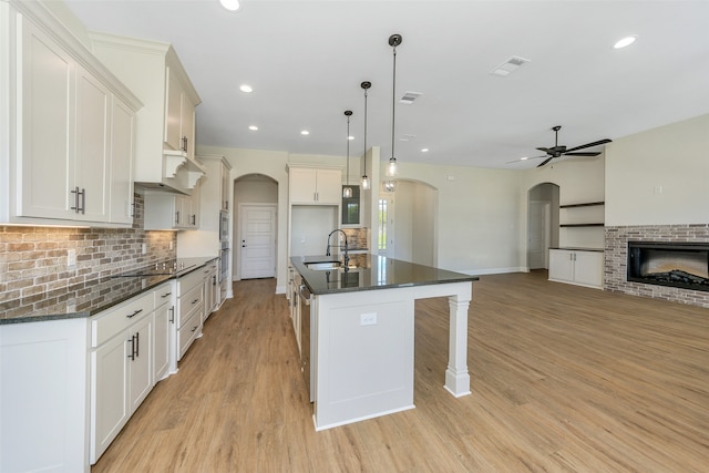 kitchen featuring an island with sink, pendant lighting, ceiling fan, and light hardwood / wood-style floors