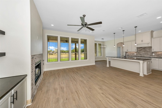 3043 Sunrise Trl, Weatherford, TX 76088 - unfurnished living room with visible vents, a fireplace, a ceiling fan, and light wood finished floors