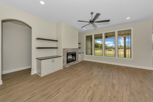 unfurnished living room featuring ceiling fan, light hardwood / wood-style floors, and a brick fireplace