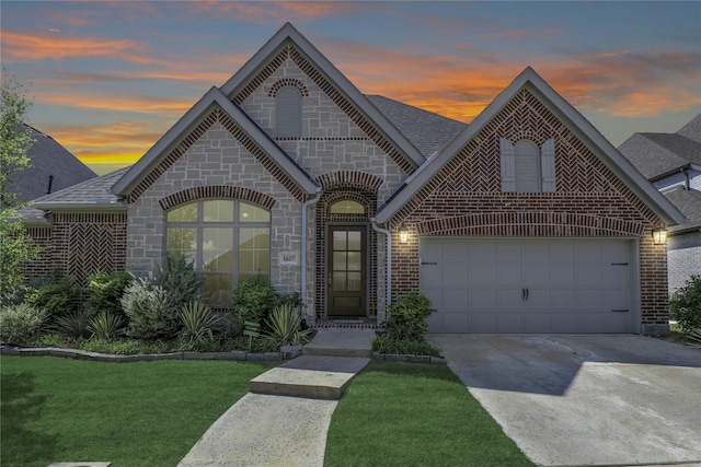 french country inspired facade with an attached garage, brick siding, driveway, and a shingled roof