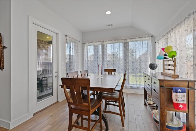 dining space featuring a wealth of natural light, visible vents, wood finished floors, and vaulted ceiling