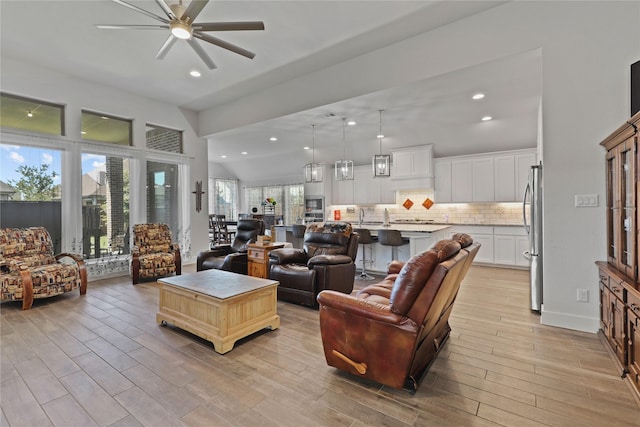 living room with recessed lighting, lofted ceiling, light wood-style floors, and a ceiling fan