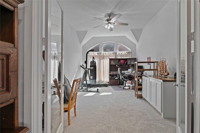 workout room with vaulted ceiling, light colored carpet, and ceiling fan