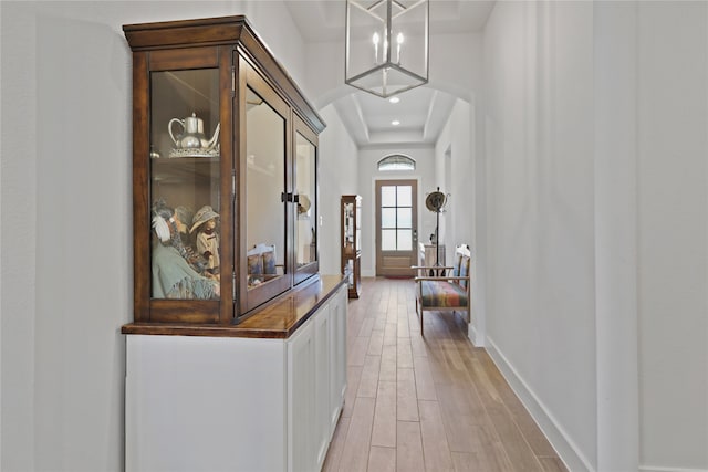 corridor featuring recessed lighting, light wood-type flooring, arched walkways, and baseboards