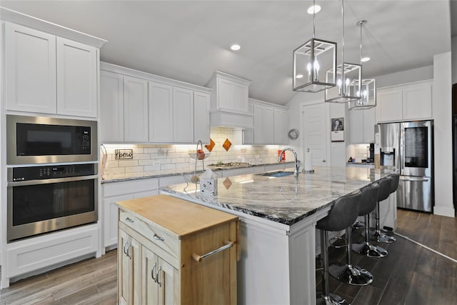 kitchen featuring stainless steel appliances, an island with sink, sink, and white cabinets