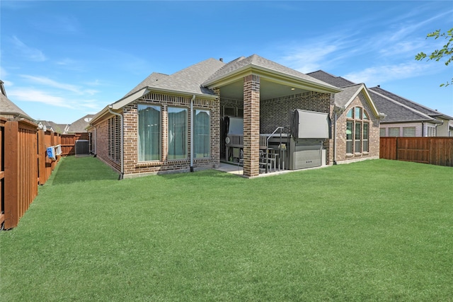 rear view of house with brick siding, a lawn, and a fenced backyard